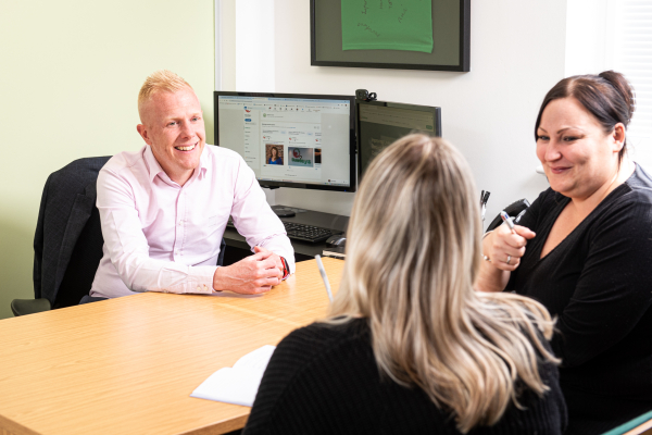 Three members of our team talking and smiling during a conversation